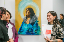 Three people smiling and talking during an art show