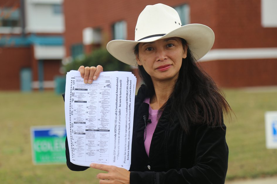 Woman in hat holding a sample ballot